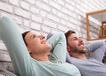 A man and woman smiling while laying on a couch, exuding peace of mind - Legacy Law Centers