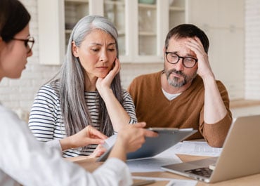 A man and woman focused on a laptop, while another man observes them. Image relates to 'Estate Planning Mistakes' - Legacy Law Centers