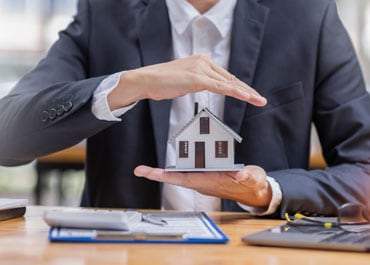 Man in suit holding house model - Legacy Law Centers