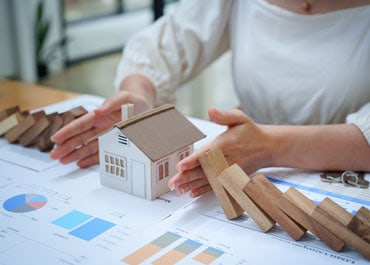 A woman holding a house model on a table, symbolizing Estate Plan - Legacy Law Centers