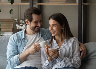 A man and woman sitting on a couch holding coffee cups - Legacy Law Centers
