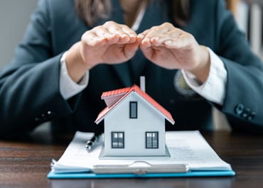 Trust Funding represented by a woman in a suit holding a house model - Legacy Law Centers
