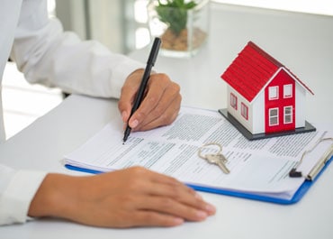 Real estate agent signing contract with house model for Estate Planning - Legacy Law Centers