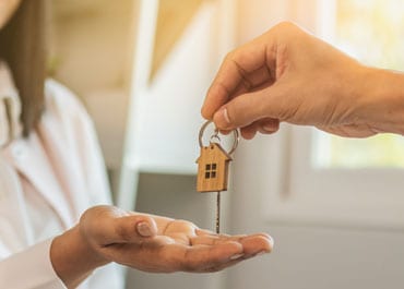 Man handing house key to woman, symbolizing property transfer - Legacy Law Centers