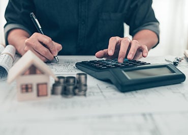 A man calculating house cost with a calculator. Image for Estate Planning Preparation - Legacy Law Centers