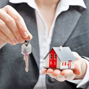  A lady holding a small home structure and home key representing estate planning -  Legacy Law Centers.